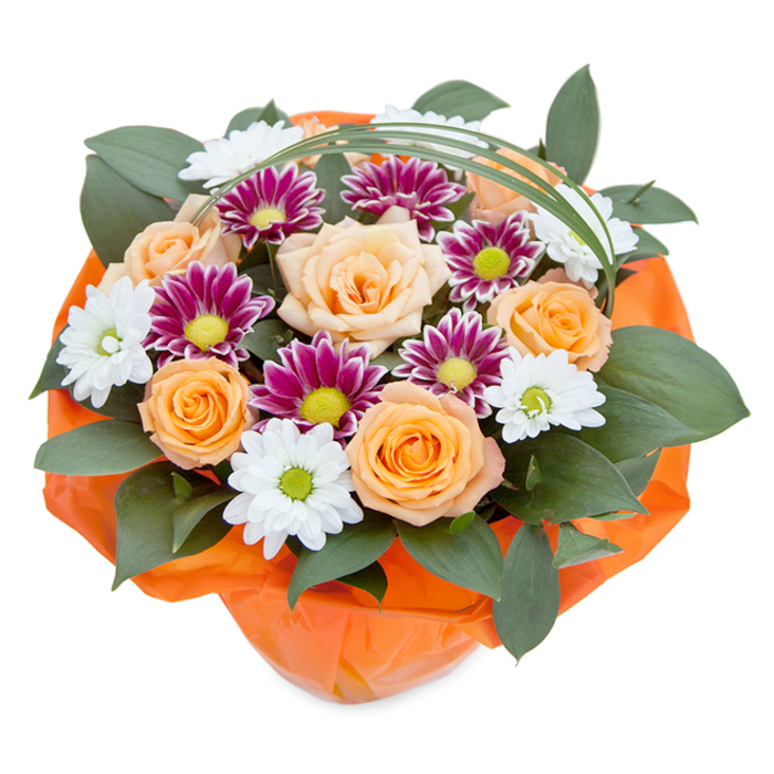 From a softly sunlit overhead vantage, this luxurious floral bouquet captures the modern yet timeless style so beloved in Kentish Town. At its centre, generous roses display petals that transition from the subtlest peach to a lively sunrise orange, their lofty blooms recalling cheerful window boxes along Fortess Road. Dotting the arrangement are clusters of delicate white chrysanthemums with bright green hearts, reminiscent of the classic English daisies that pepper Kentish Town's green spaces, paired with sumptuous magenta blooms whose petals spiral tightly around their vivid lime-green centres, offering dramatic impact and visual depth. Supporting the flowers, abundant dark foliage unfurls softly, perhaps ruscus or leafy greens akin to those found in Grove Gardens, lending strength and botanical structure. Thin, arched blades of bright bear grass trace a graceful line across the top, giving the bouquet a fluid finish and a whisper of sophistication. At the base, crinkled orange cellophane echoes the warmth of the roses, wrapping the composition with a sense of care and celebration. With its blend of colours, lively freshness, and expert craftsmanship, this bouquet is the embodiment of generosity and warmth, the sort Kentish Town is known for-perfect for sharing joy, marking milestones, or elevating the everyday.